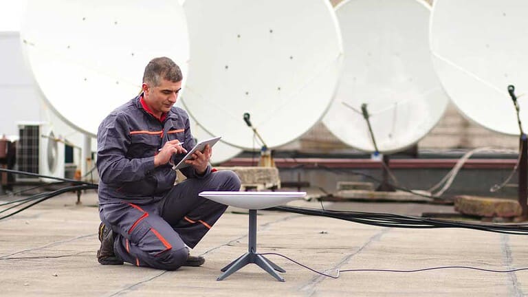 a man installs a starlink internet dish