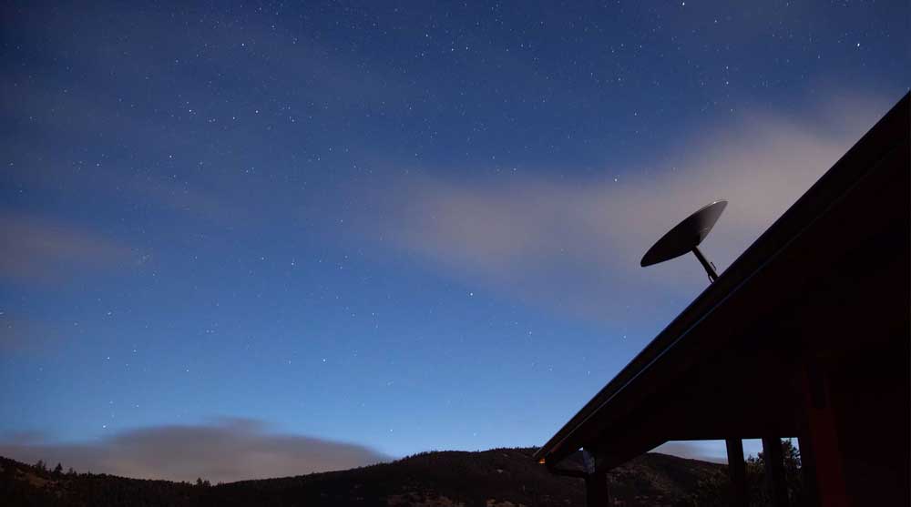 A Satellite dish pictured at night on a roof